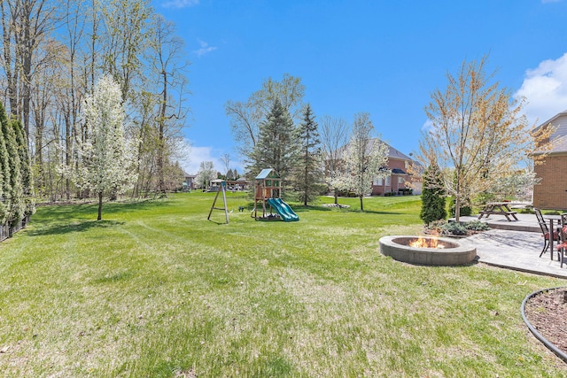 view of yard featuring a playground, an outdoor fire pit, and a patio area