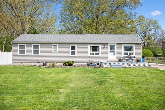 rear view of property featuring fence, a deck, roof with shingles, crawl space, and a lawn