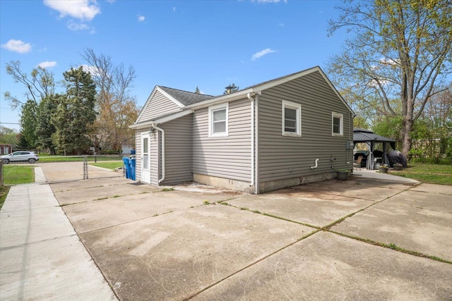view of side of home featuring a gazebo, fence, and driveway