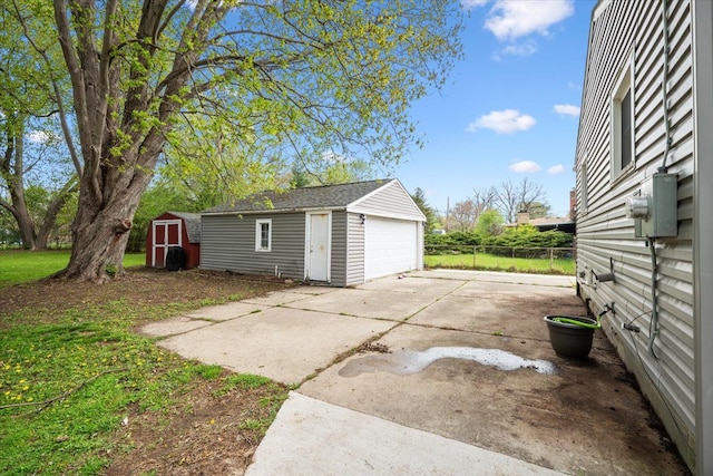 detached garage featuring a storage shed and fence