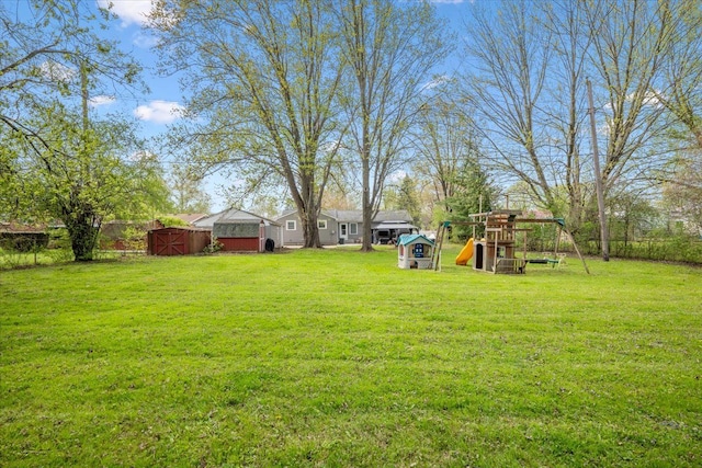 view of yard with an outdoor structure, a playground, a shed, and fence