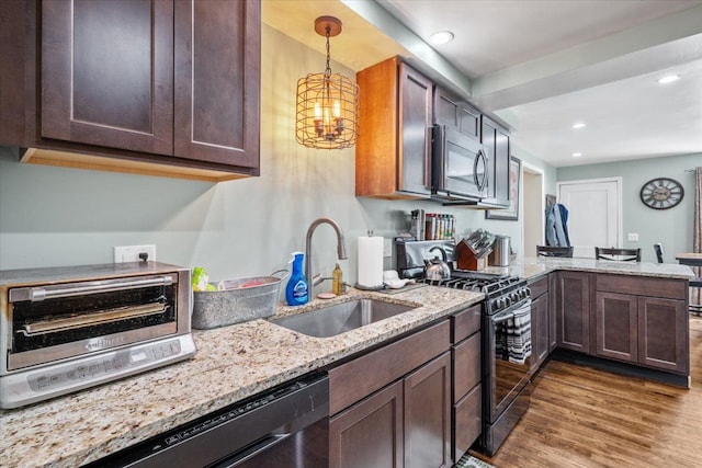 kitchen with appliances with stainless steel finishes, hanging light fixtures, a sink, a peninsula, and wood finished floors