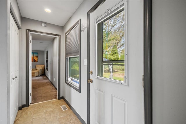 doorway with baseboards, stone finish flooring, and visible vents