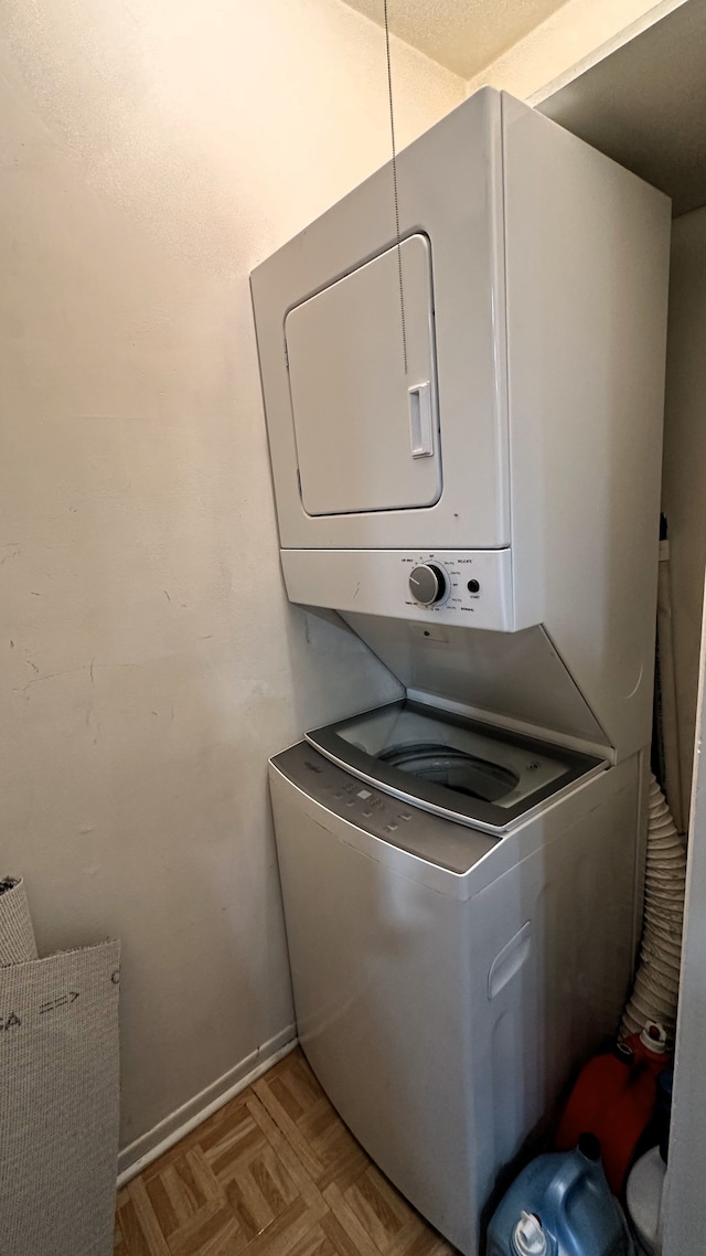 laundry room featuring baseboards and stacked washer and dryer