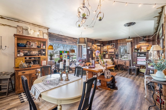 dining space featuring a notable chandelier, wood finished floors, and wooden walls