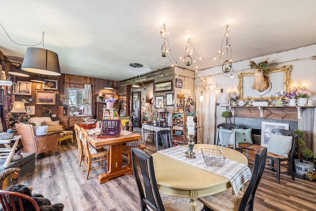 dining area with wood finished floors, wooden walls, and a fireplace