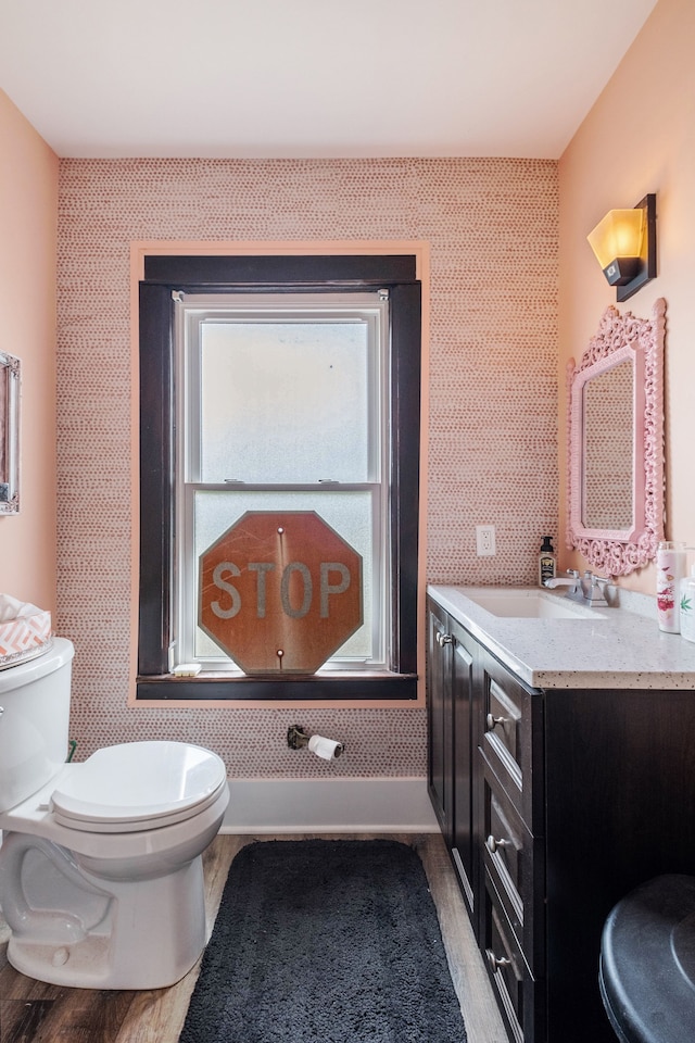 bathroom featuring vanity, wood finished floors, toilet, and wallpapered walls
