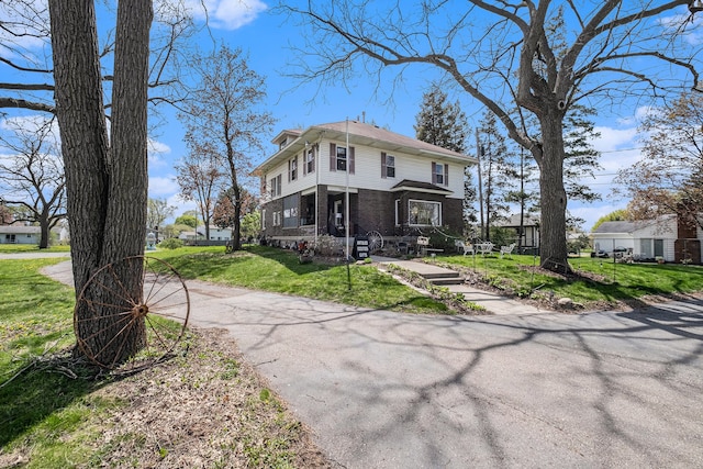 traditional style home with brick siding, a front yard, and aphalt driveway