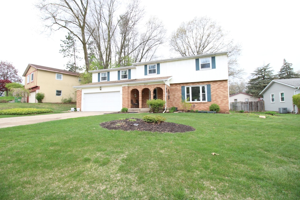 traditional-style house featuring a front lawn, fence, covered porch, brick siding, and driveway