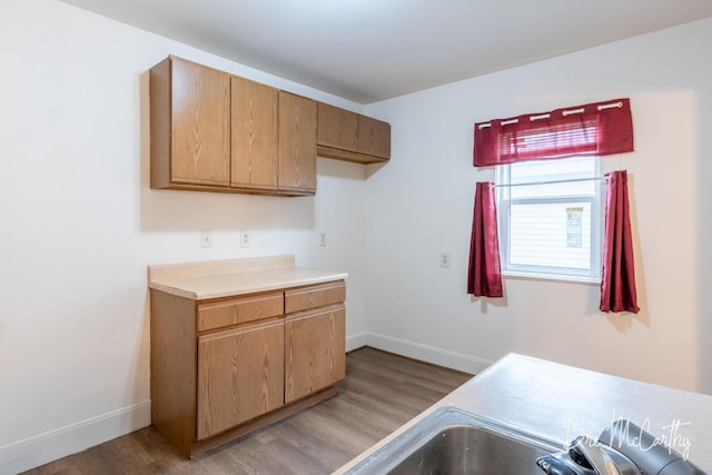 kitchen featuring baseboards, light countertops, and wood finished floors