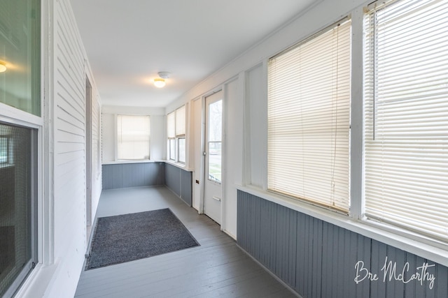 unfurnished sunroom featuring wood walls and wood finished floors