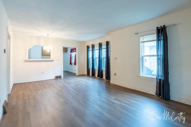 unfurnished living room featuring baseboards, wood finished floors, and a chandelier