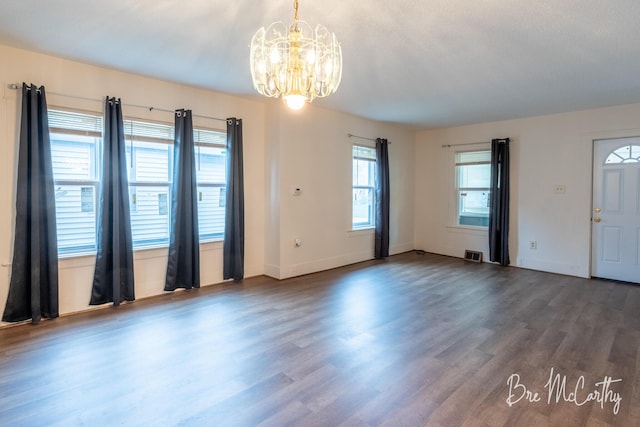 interior space with baseboards, visible vents, wood finished floors, and a chandelier
