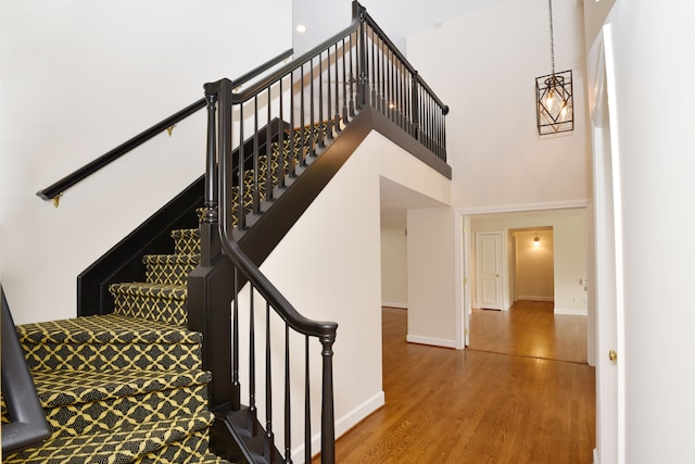 32824 Outland Trl, Bingham Farms, MI 48025 - stairs featuring baseboards, an inviting chandelier, wood finished floors, and a towering ceiling