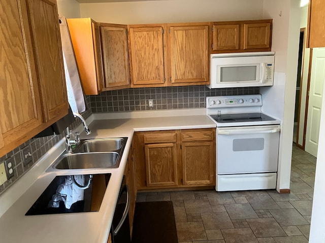 kitchen featuring a sink, white appliances, light countertops, stone finish flooring, and tasteful backsplash