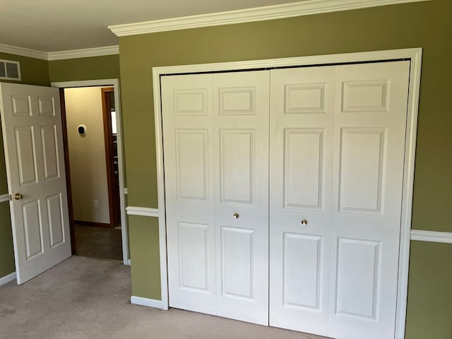 unfurnished bedroom with visible vents, crown molding, baseboards, a closet, and light carpet