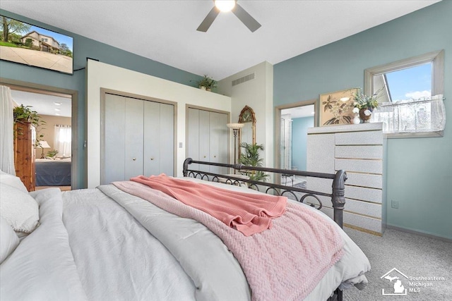 bedroom with two closets, a ceiling fan, visible vents, and carpet floors