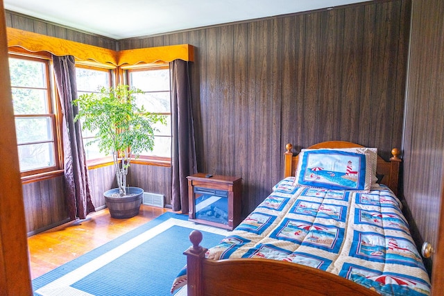 bedroom featuring wooden walls, visible vents, and wood finished floors
