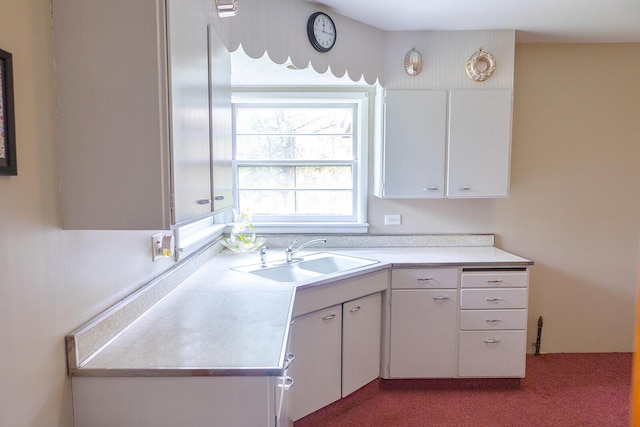 kitchen with a sink, carpet, white cabinets, and light countertops