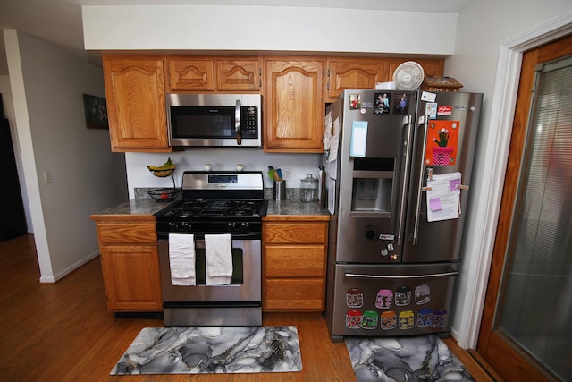 53240 Hemlock Lake Rd, Marcellus, MI 49067 - kitchen with baseboards, appliances with stainless steel finishes, brown cabinetry, and wood finished floors