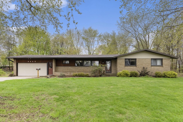 view of front of property with brick siding, a garage, a front yard, a chimney, and concrete driveway