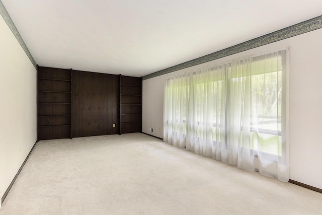 carpeted spare room featuring baseboards, built in features, and a wealth of natural light