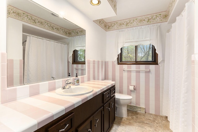 full bath featuring tile walls, a wainscoted wall, vanity, and toilet