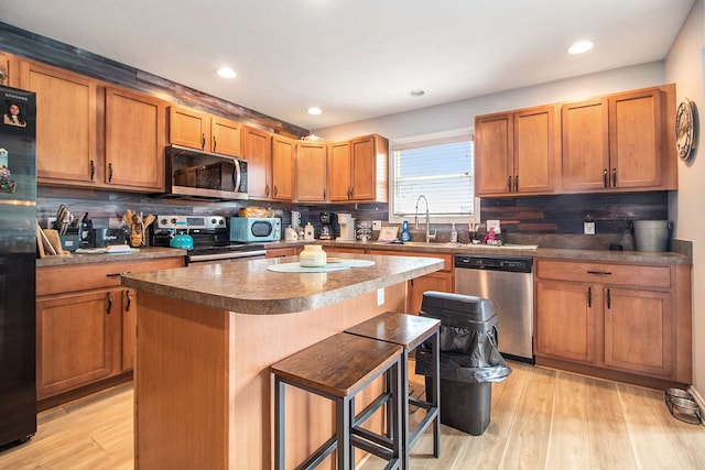 15000 Tiara Ave, Monroe, MI 48161 - kitchen with a sink, appliances with stainless steel finishes, decorative backsplash, a kitchen bar, and light wood-style floors