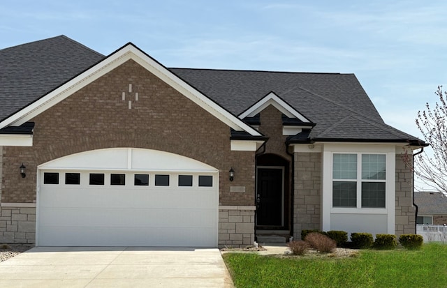 view of front of property with roof with shingles, a garage, driveway, and stone siding