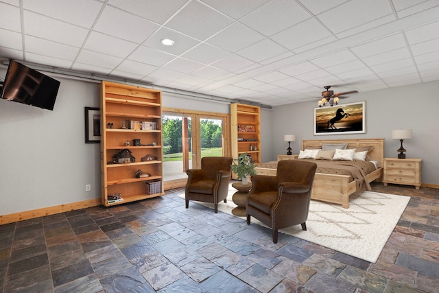 bedroom featuring stone tile floors, baseboards, access to exterior, and a paneled ceiling
