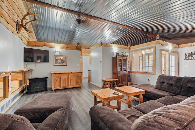 living room with light wood-type flooring, baseboards, beam ceiling, and a fireplace