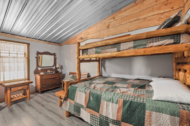 bedroom with wood finished floors and lofted ceiling