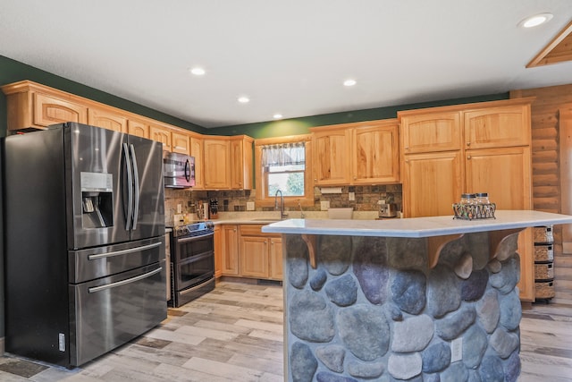 kitchen featuring light wood-style floors, a sink, appliances with stainless steel finishes, and light countertops