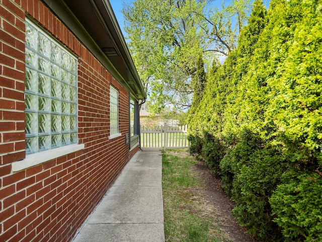 view of side of home with brick siding and fence