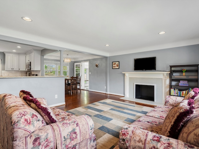 living room featuring wood finished floors, recessed lighting, baseboards, and a fireplace with flush hearth