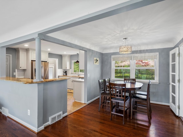 dining room featuring wood finished floors, baseboards, and ornate columns
