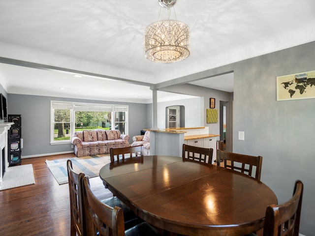 dining space with wood finished floors, a fireplace with raised hearth, a chandelier, baseboards, and recessed lighting