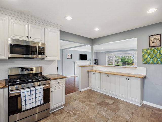 kitchen featuring stainless steel appliances, baseboards, white cabinetry, light stone finish floors, and recessed lighting