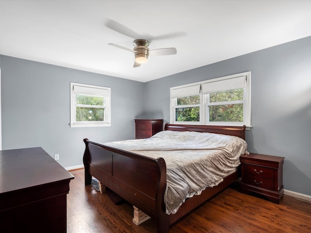 bedroom featuring multiple windows, baseboards, wood finished floors, and a ceiling fan