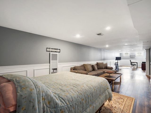 bedroom featuring a wainscoted wall, hardwood / wood-style flooring, a decorative wall, and recessed lighting
