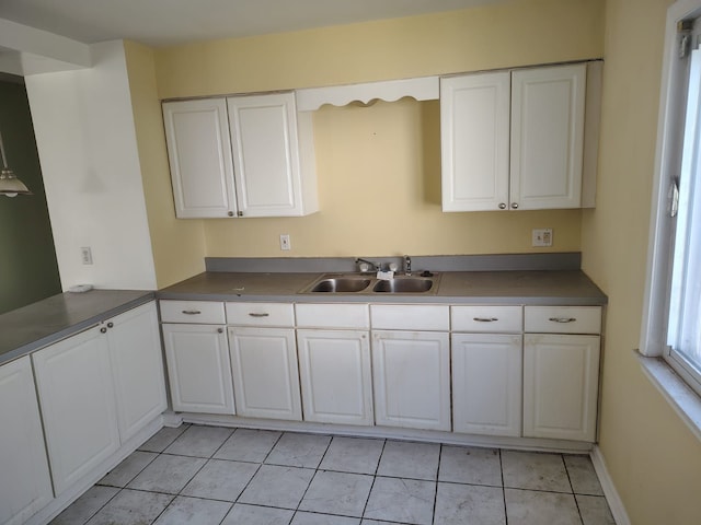 kitchen featuring white cabinets, light tile patterned floors, dark countertops, and a sink