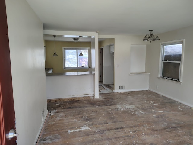 unfurnished dining area with visible vents, baseboards, an inviting chandelier, and hardwood / wood-style flooring