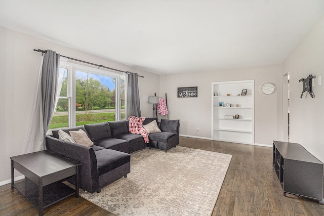 living area with baseboards, dark wood-style floors, and built in features