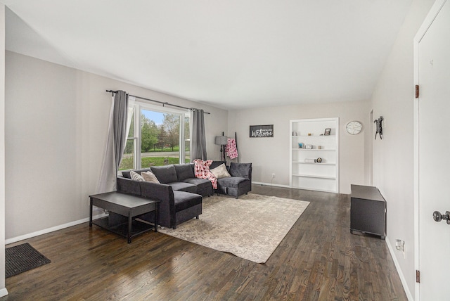 living room featuring baseboards, built in features, and dark wood-type flooring