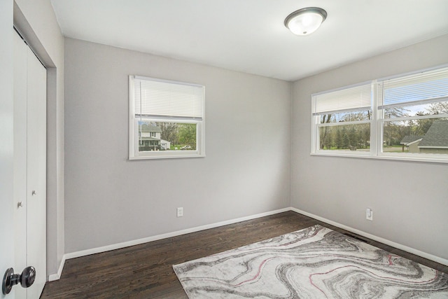 unfurnished bedroom featuring baseboards, wood finished floors, and a closet