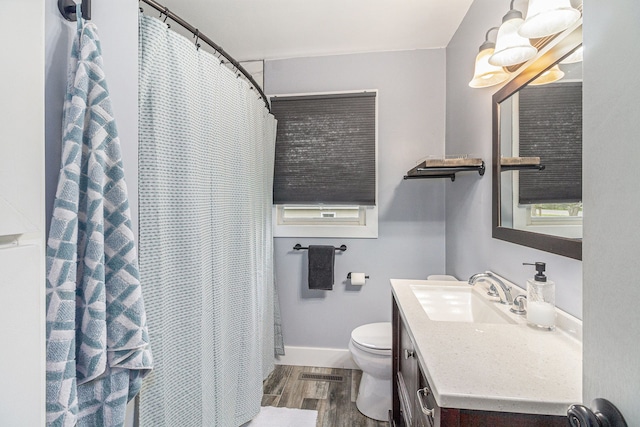 bathroom featuring vanity, toilet, baseboards, wood finished floors, and visible vents
