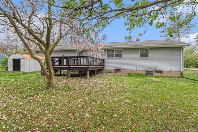 rear view of property with a yard, a deck, an outdoor structure, and a shed