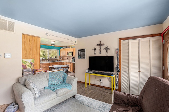 living area with baseboards, visible vents, and wood finished floors
