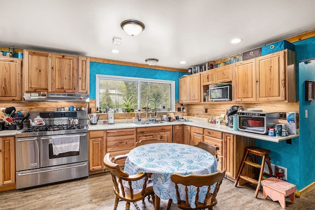 kitchen featuring a sink, gas stove, light wood-style floors, light countertops, and extractor fan
