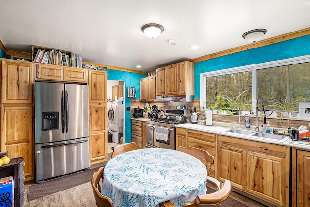 kitchen with wood finished floors, a sink, light countertops, stainless steel appliances, and washer and clothes dryer